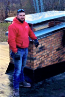 A man standing near a chimney rebuild, striking a pose, showcasing the completed work