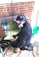 A man wearing a mask, working on the installation of a fireplace, emphasizing safety and craftsmanship